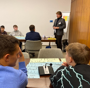 Schüler:innen hören einem Teamer zu, der zu Themen der Landespolitik spricht