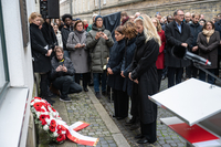 Das Präsidium steht vor dem niedergelegten Kranz, im Hintergrund sind Zuschauer zu sehen.
