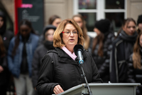 Antje Grotheer steht am Rednerpult. Im Hintergrund sind Menschen zu sehen.