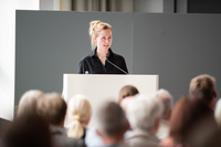 Marie Müller-Elmau steht am Rednerpult, vor ihr sind die Köpfe der Gäste zu sehen.